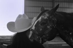 Black and white photograph of a girl in a white cowboy hat with a horse